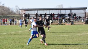 Soccer players in action on a sunny day in Vásárosnamény, Hungary with spectators watching.